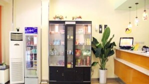 Un área de recepción con un refrigerador, una vitrina de vidrio, una planta en maceta y un ordenador portátil sobre la encimera.
