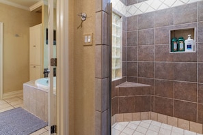 Een badkamer met een douche, een wastafel en een wastafelmeubel. Er staan toiletartikelen aan de muur.