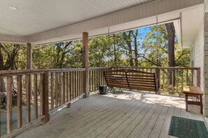 Une véranda couverte avec une balustrade en bois, un banc et une petite table.