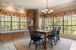 Un coin repas avec une table en bois, des chaises noires et un lustre.