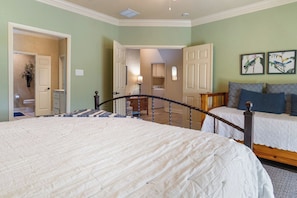 Een slaapkamer met twee bedden, een trap en een gang naar een badkamer.