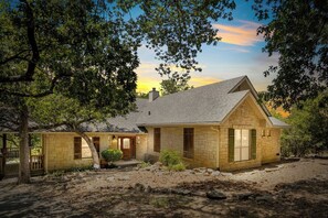 Een stenen herenhuis met twee verdiepingen, een puntgevel, een voortuin en een aangelegde tuin.