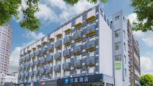 Ein mehrstöckiges Hotel mit Balkonen, einem sichtbaren Schild für '汉庭酒店' und freiem Blick zum Himmel.