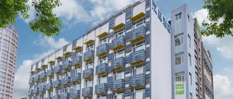 A multi-story hotel with balconies, a visible sign for '汉庭酒店', and a clear view of the sky.