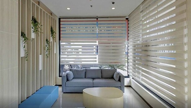 Ein modernes Interieur mit einer Couch, einem Couchtisch und einer Wand mit Jalousien.
