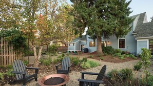 A backyard with a fire pit, outdoor seating, and a house with a sloped roof. - Luxe remodel, three King ensuites, walk to 3rd St (McMinnville)