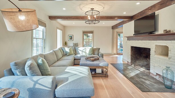 A spacious living room with a large sectional sofa, a fireplace, and a television mounted above it. - Luxe remodel, three King ensuites, walk to 3rd St (McMinnville)