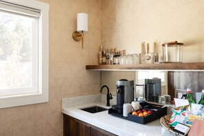 A kitchen with a sink, coffee maker, and various kitchen items on the counter.