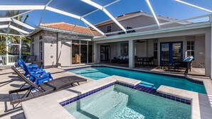 Een zwembadgedeelte met ligbedden, een jacuzzi en een overdekt terras.