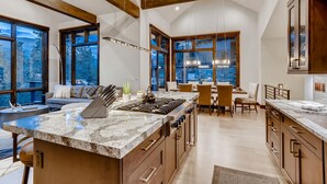 A spacious kitchen with a large island, wooden beams, and large windows offering views of the outdoors. - 🏆 Breck Ski Views | Gondola Access | Hot Tub | 3 Kings | Sleeps 8 (Breckenridge)