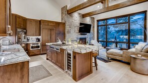 A spacious kitchen with a large island, wooden cabinets, and a stone accent wall. - 🏆 Breck Ski Views | Gondola Access | Hot Tub | 3 Kings | Sleeps 8 (Breckenridge)