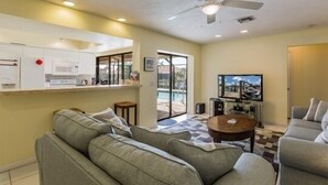 Ein Wohnzimmer mit Sofa, Couchtisch, Fernseher und Deckenventilator.