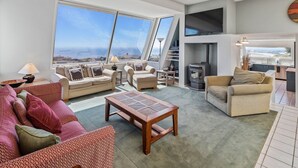 A modern living room with a large window, a fireplace, and a dining area. - Dazzling Luxury Ocean views, Hot Tub, Golf, AC, Theater, Chef Options @SwitiHoso (Bodega Bay)