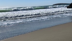 A beach with waves crashing onto the shore, a clear sky, and a distant landform. - Dazzling Luxury Ocean views, Hot Tub, Golf, AC, Theater, Chef Options @SwitiHoso (Bodega Bay)