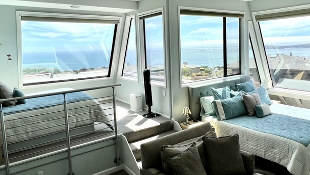 A bedroom with a bed, a sofa, and a staircase. - Dazzling Luxury Ocean views, Hot Tub, Golf, AC, Theater, Chef Options @SwitiHoso (Bodega Bay)