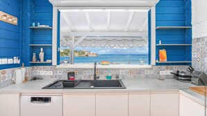 Een keuken met uitzicht op zee, een spoelbak en een afwassysteem.