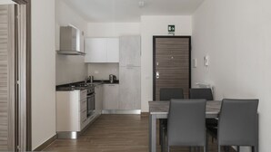 A modern kitchen with a dining area, a built-in oven, and a coffee machine.