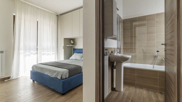 A bedroom with a bed, a bathroom with a bathtub and sink, and a closet.