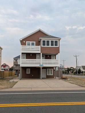 A two-story residential building with a balcony, a garage, and a driveway. - Diggin’ It- Beach Road, Private pool & Hot tub (Kill Devil Hills)