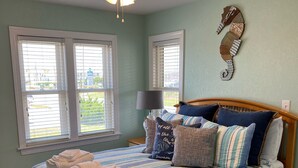 Une chambre à coucher avec un lit, un ventilateur de plafond et une décoration murale représentant un hippocampe.