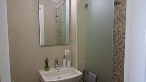 Un baño con lavamanos, espejo y ducha.