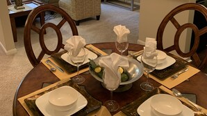 A dining area with a round table set for four, including plates, cutlery, and glasses.