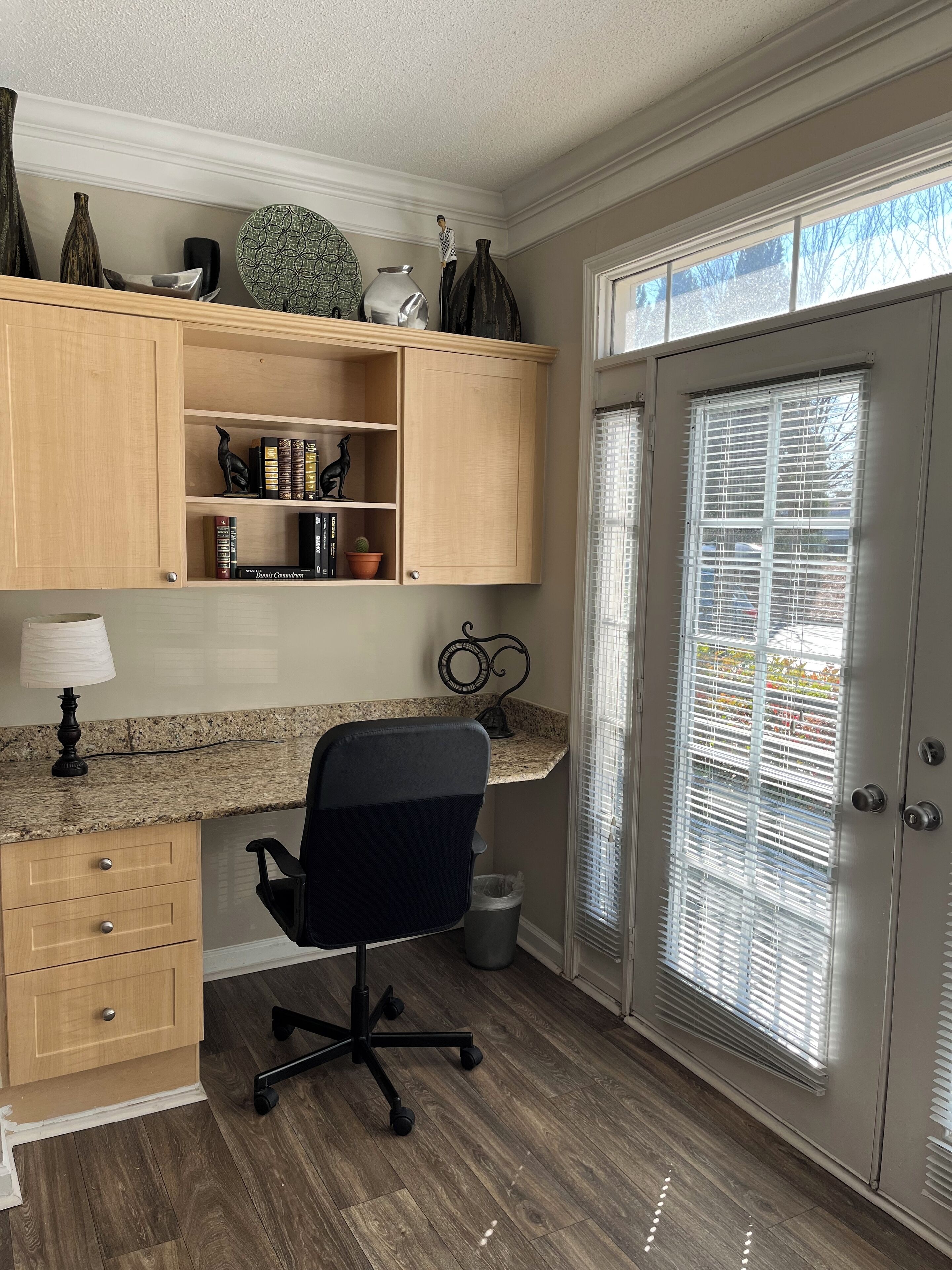 A home office with a desk, chair, and shelves with books and decorative items.