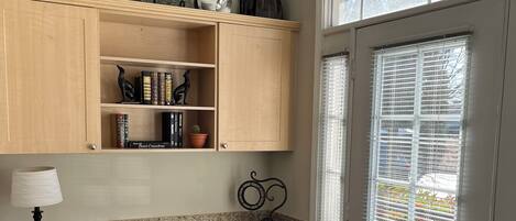 A home office with a desk, chair, and shelves with books and decorative items.