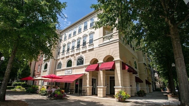 A building with a beige facade, arched windows, and red awnings.