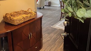 A wooden cabinet with drawers, a wicker basket on top, and a plant in the foreground.