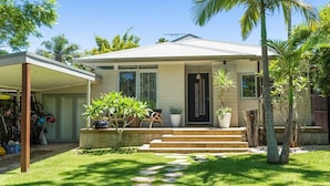 Una casa a un piano con un portico coperto, un ingresso e un piccolo giardino antistante con un vialetto che conduce alla porta.