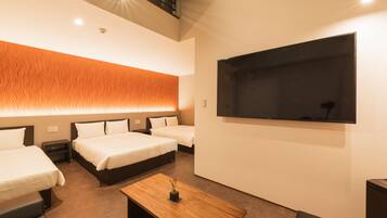 A hotel room with two beds, a wooden table, a flat-screen TV, and a wall-mounted shelf.