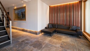 Een moderne lobby met een modulaire bank, een trap en een groot schilderij aan de muur.