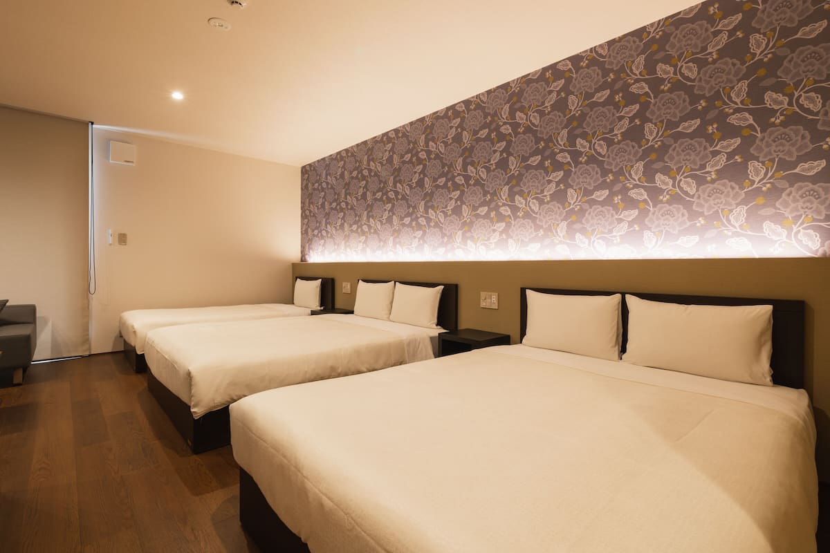 Une chambre d’hôtel avec deux lits, un plancher en bois et un papier peint à motifs floraux.