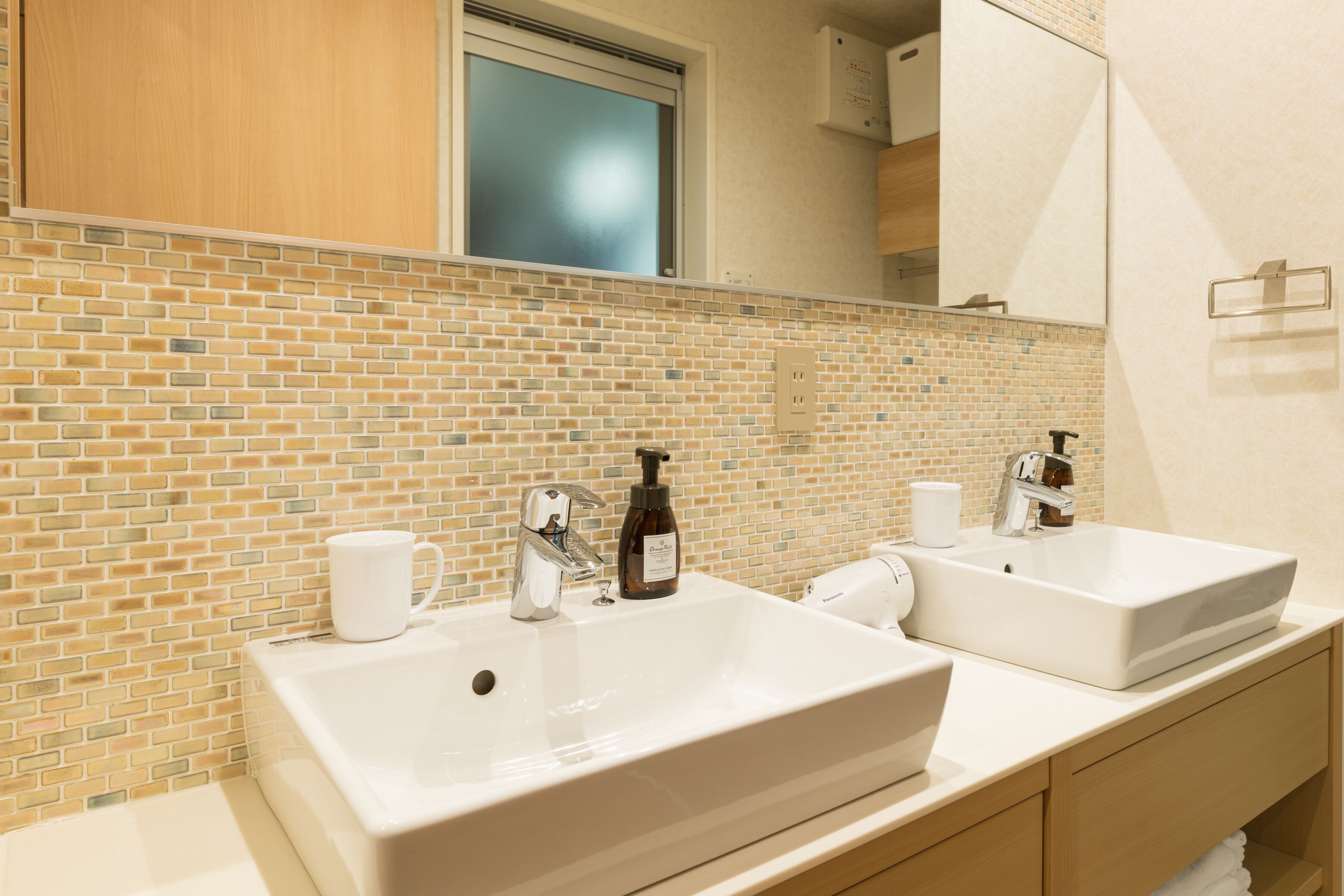 A bathroom with two sinks, a mirror, and a tiled backsplash.