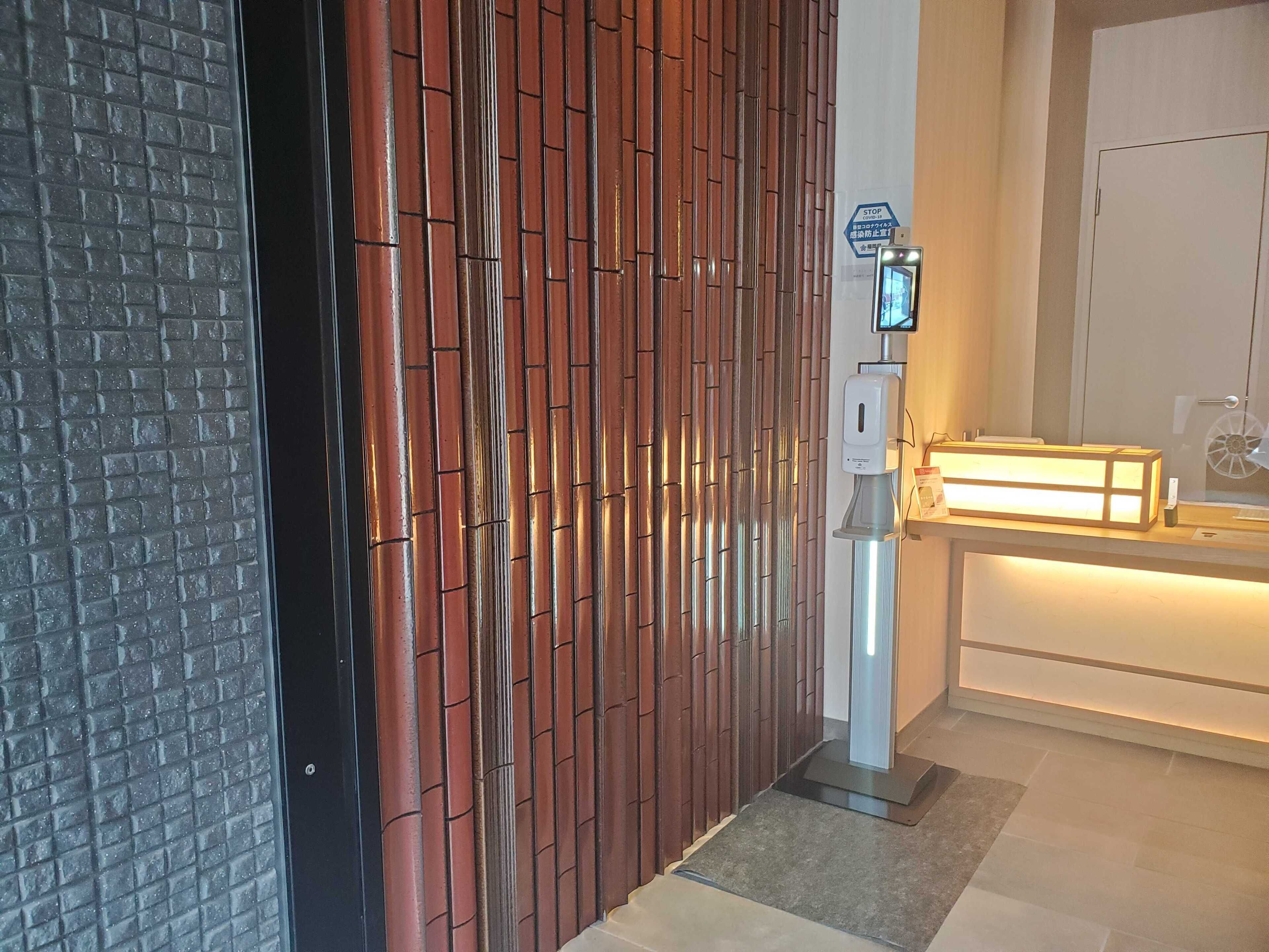 A modern interior with a wooden panel wall, a reception desk with a digital screen, and a white door.