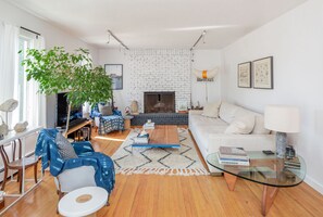 Cozy living space with a brick fireplace, comfortable sofa, and a large potted plant.