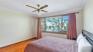 Un dormitorio con cama, ventilador de techo y ventana con cortinas.