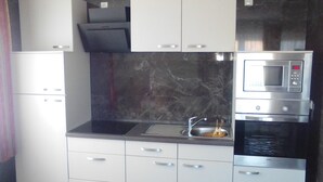 A modern kitchen with white cabinets, a black marble backsplash, and stainless steel appliances including a microwave and oven.