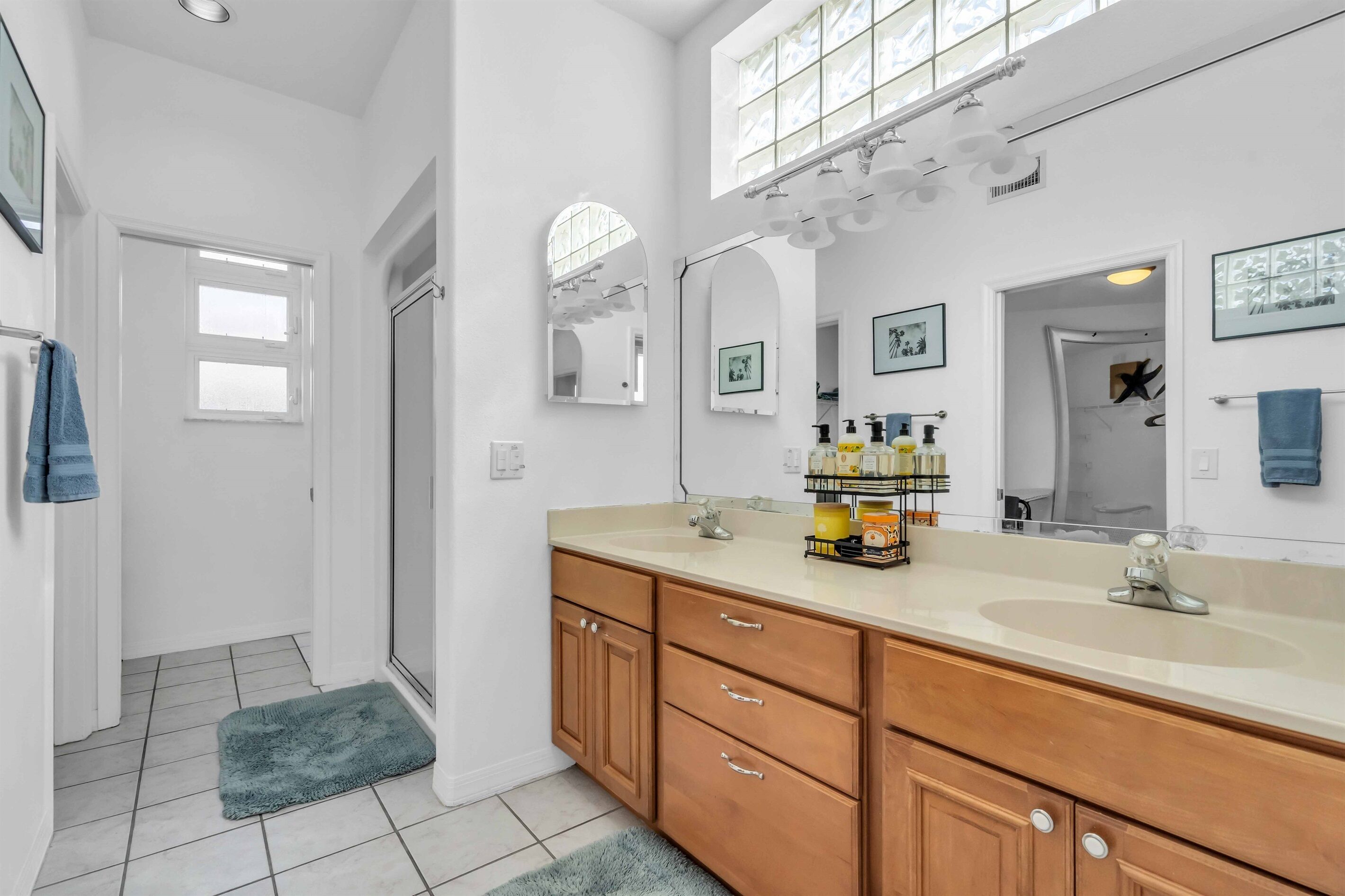 A modern bathroom with a large mirror, a double sink vanity, and a shower area.