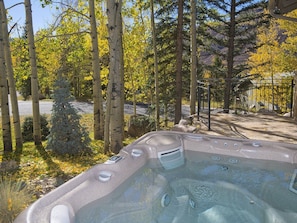 A hot tub surrounded by birch trees and a fenced area.