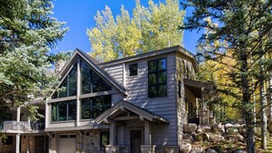 Une maison à deux étages, avec des fondations en pierre, de grandes fenêtres et un garage.