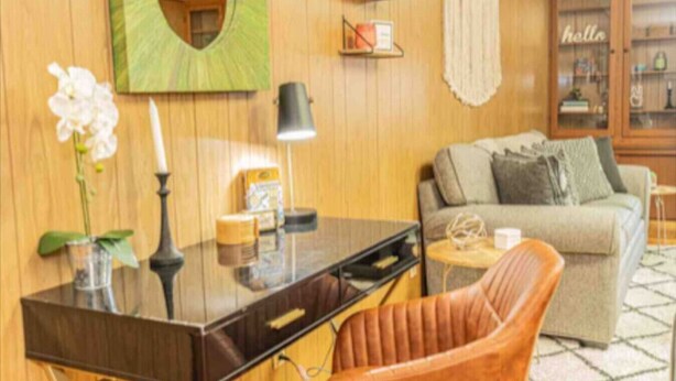 Una habitación con un escritorio de madera, un sillón de cuero, un sofá y un aparador con estantes.