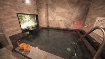 A hot tub with a television screen, a sign with text, and a wooden floor.