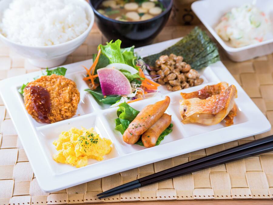 A white rectangular plate with various dishes including fried items, rice, and vegetables.