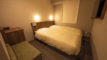 A hotel room with a bed, a bedside table, a chair, and a window.