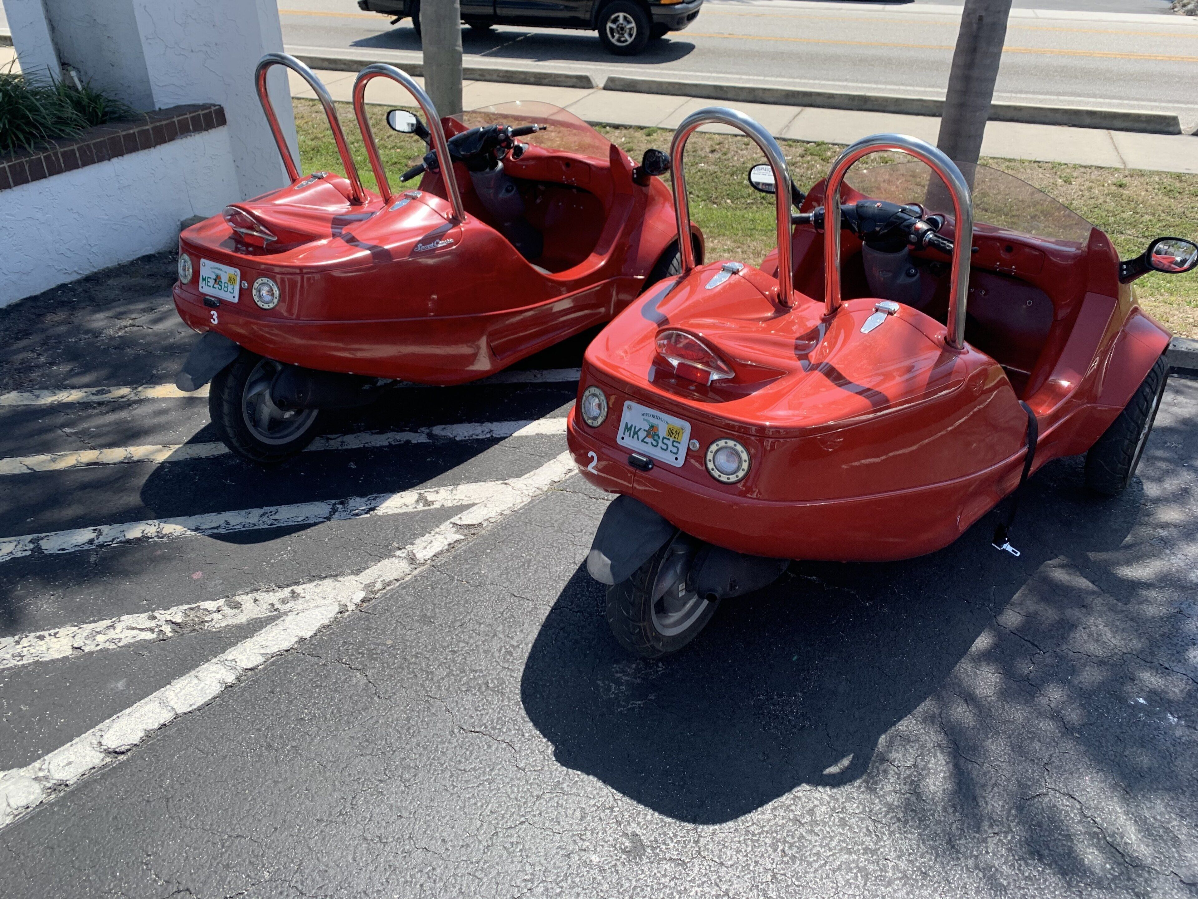 Two red bumper cars parked in a lot with visible license plates.