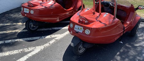 Two red bumper cars parked in a lot with visible license plates.