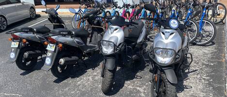 A row of motorcycles parked in front of a building with signage for a salon and a kayak rental service.