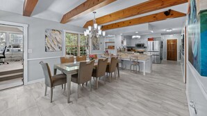 A spacious kitchen with modern appliances, a dining area with a large table and chairs, and a view of the outdoors through large windows. -  AMAZING & A PARTY BARN… HOT TUB, PL TBl, PNG PNG, & ARCADE!  ACCESS TO POOLS! (West Des Moines)